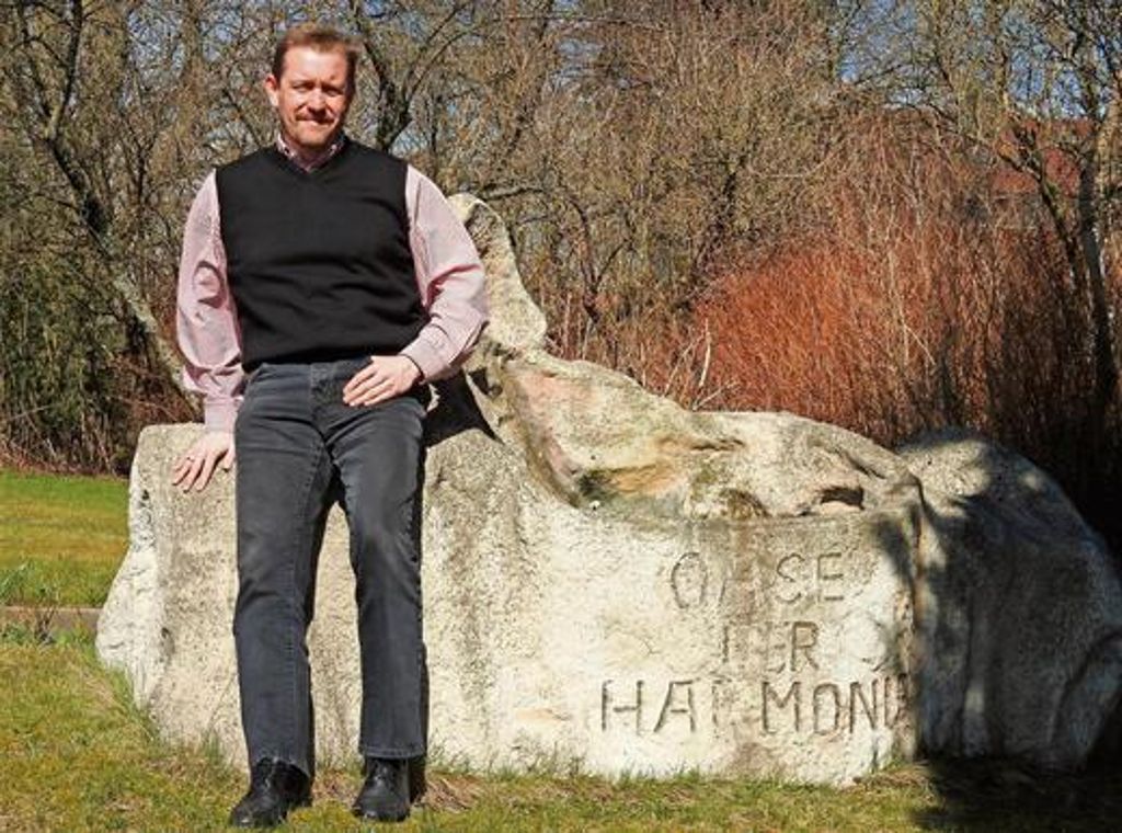 Kai Hammerschmid vor einem Sitzfelsen im Garten des Unternehmens. Klar, der Steinist aus Beton. 	Fotos: Bäumler