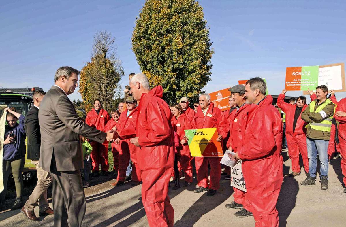Der bayerische Ministerpräsident Markus Söder sprach am Rande der Einweihung eines Ostbayernring-Teilstücks in Mechlenreuth bei Münchberg mit Landwirten aus Oberfranken. In rote Ganzkörperanzüge gehüllt, protestierten die Bauern gegen die Neuabgrenzung der „Roten Gebiete“.