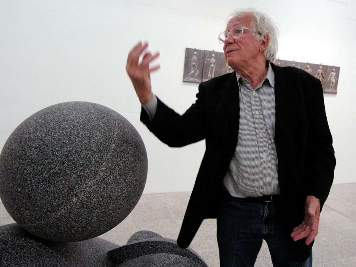 Der Bildhauer Fritz Koenig gestikuliert vor seiner Granit-Skulptur «Kugelkopf». Foto: Armin Weigel
