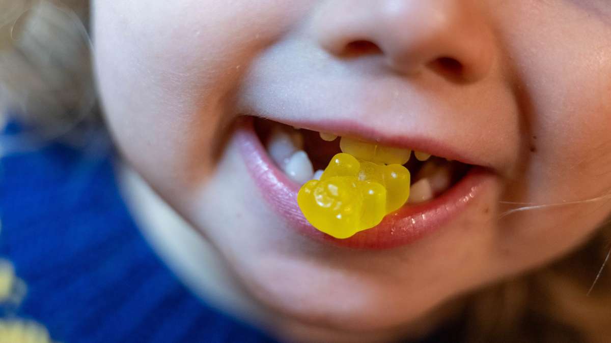 Ein Kind beißt auf ein Kinder-Vitaminbärchen.
