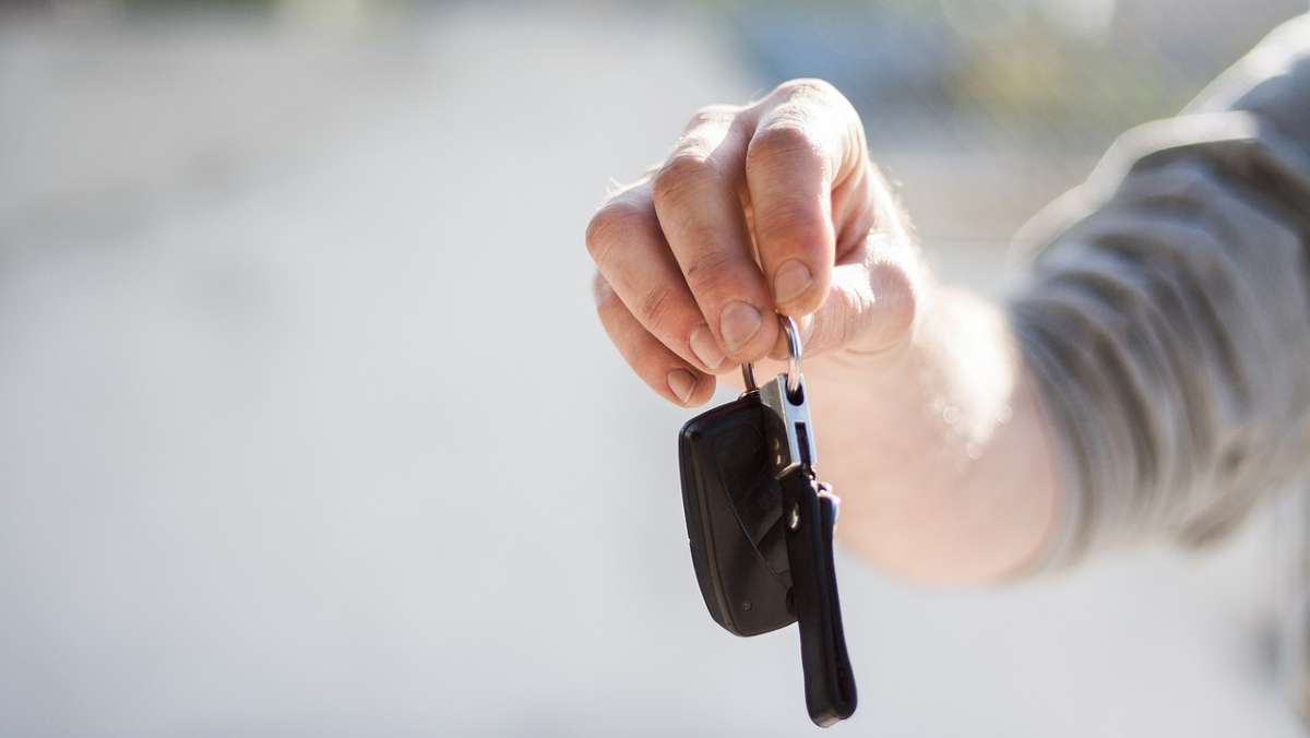 Ein junger Mann hält einen Autoschlüssel in der Hand. Symbolfoto.