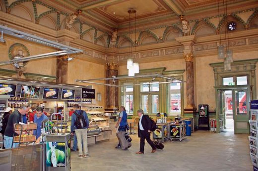 Viele auswärtige Besucher des Hofer Hauptbahnhofs bewundern die kunstvoll gestaltete Decke des historischen Speisesaals. Derzeit haben hier die Filialen einer Imbiss-Kette und eines Buch- und Zeitschriftenhandels ihr Domizil.