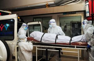 Sanitäter und Ärzte bringen einen der am Nipah-Virus Verstorbenen im indischen  Bundesstaat Kerala unter strengsten Sicherheitsvorkehrungen zur Untersuchung. Foto: AFP