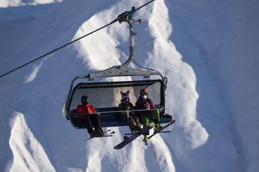Skifahrer tragen FFP2-Schutzmasken in einem Sessellift. Foto: picture alliance/dpa/KEYSTONE | Gian Ehrenzeller