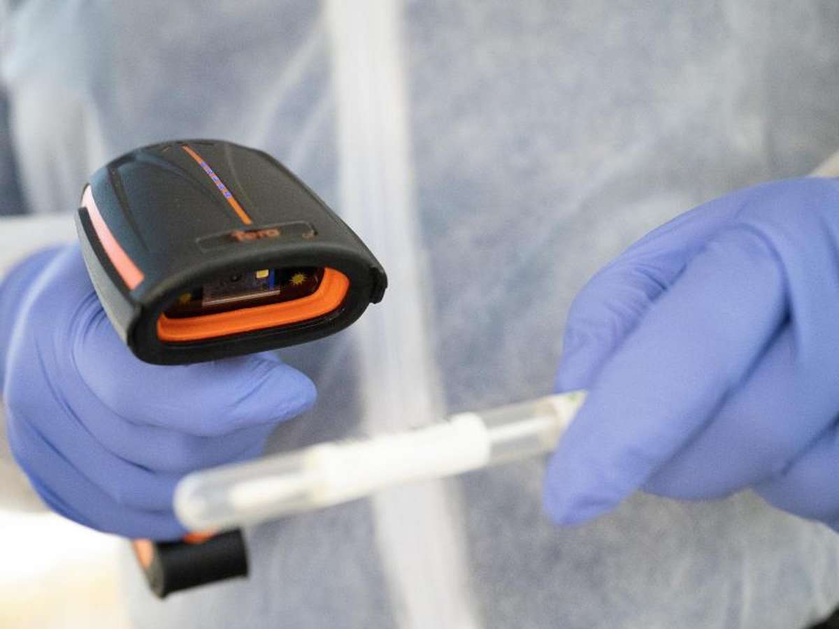 Ein Arzt in Schutzkleidung scannt ein Teststäbchen in einer mobilen Corona-Teststation. Foto: Sebastian Gollnow/dpa